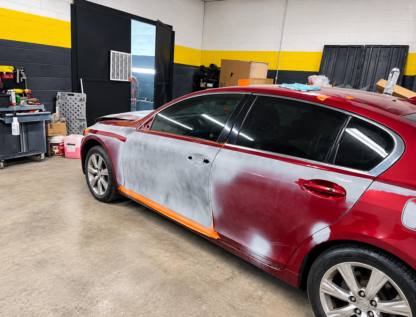 Red vehicle with body panels sanded and prepared for refinishing