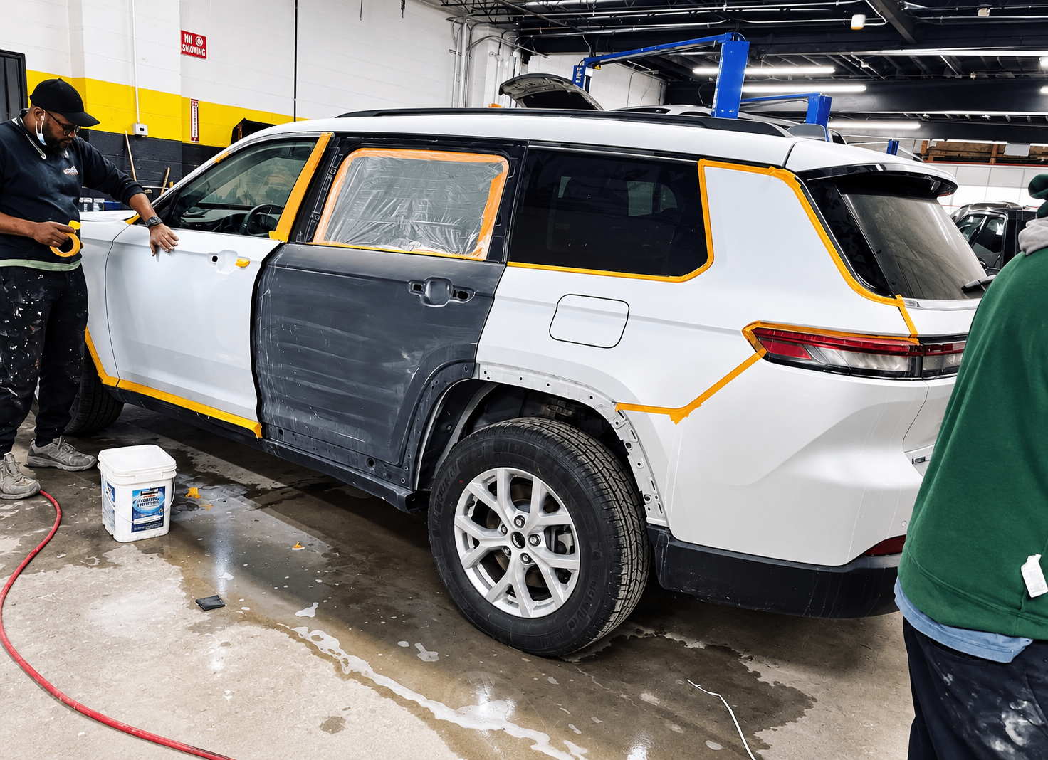 Technician masking an SUV in preparation for paint work